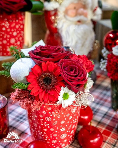 Bouquet de roses rouges et de gerberas dans un pot de Noël décoratif.